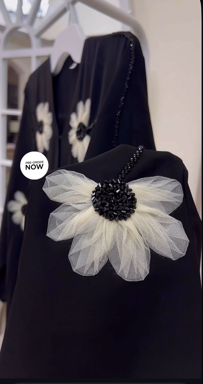 Black Abaya with a large white floral accessory on a hanger.